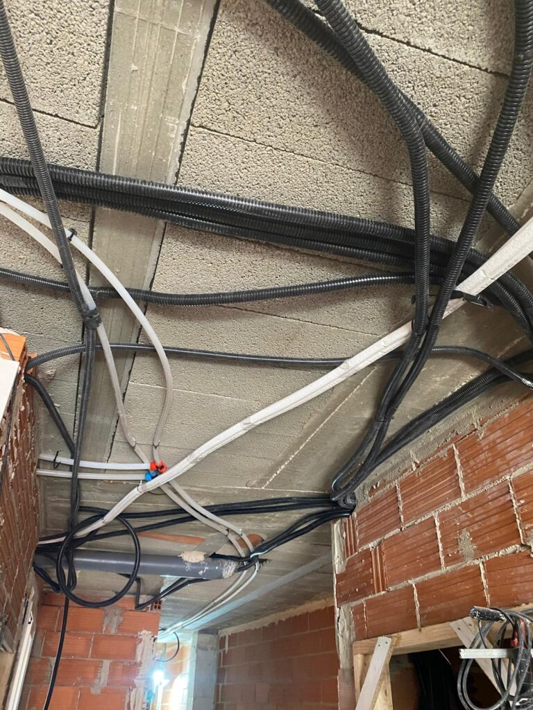 Instalación de tubería corrugada y cableado denso en techo y pared de ladrillo en obra en Valencia
