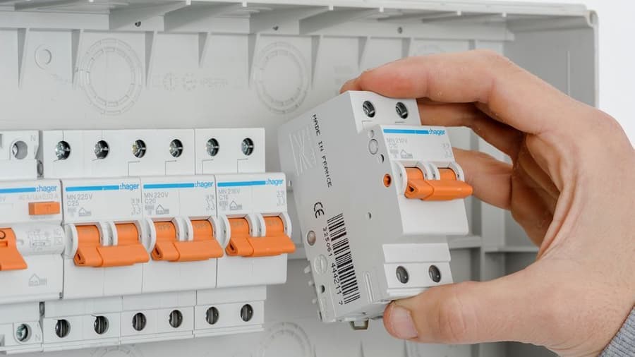 Primer plano de la mano de un electricista instalando un interruptor magnetotérmico en un cuadro de protección en Valencia